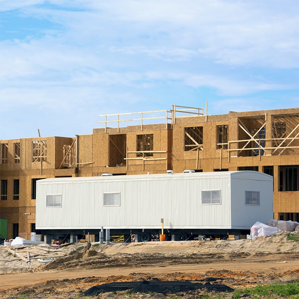 construction site office trailers are delivered using a truck and crane, and then set up using stabilizing jacks for a stable foundation